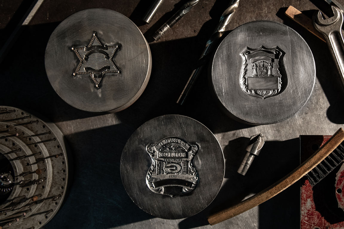 Three metal stamping dies on table for manufacturing police badges